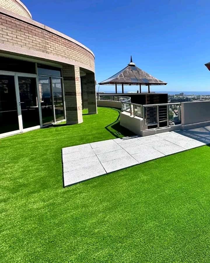 Bright artificial lawn installed on a rooftop terrace with paving slabs